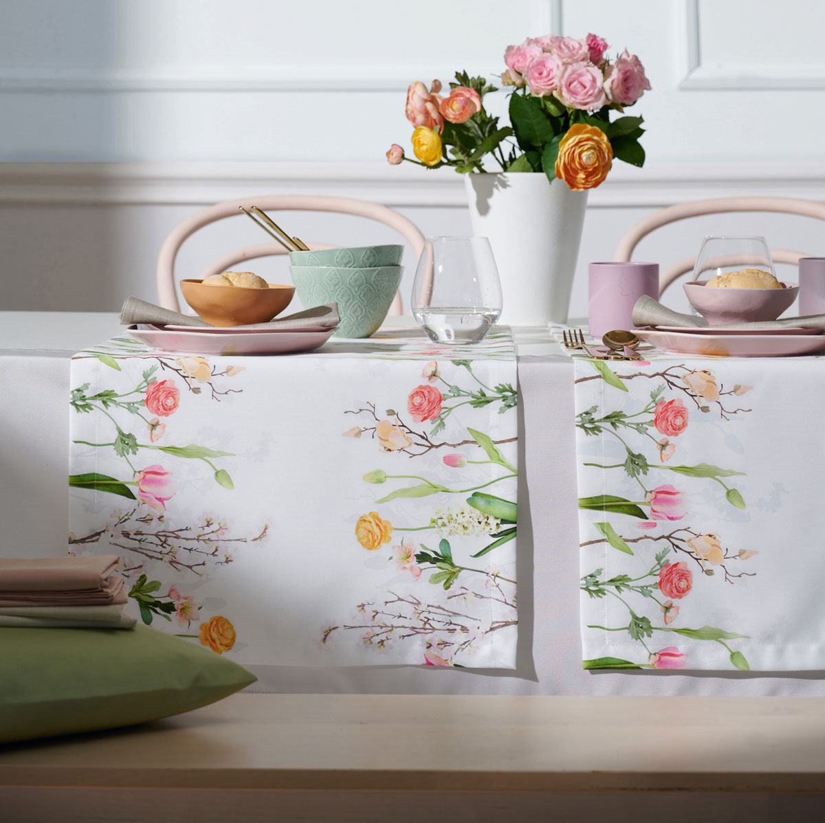 Tischläufer mit Frühlingsblumen-Dekor auf gedecktem Tisch mit Teller, Schalen und einer Vase mit Blumen