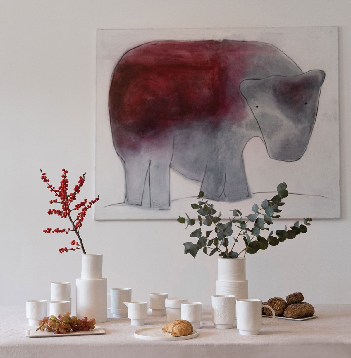 Grafik  mit Motiv Elefant an der Wand - weiße Vasen, Tassen, Teller auf Tisch davor